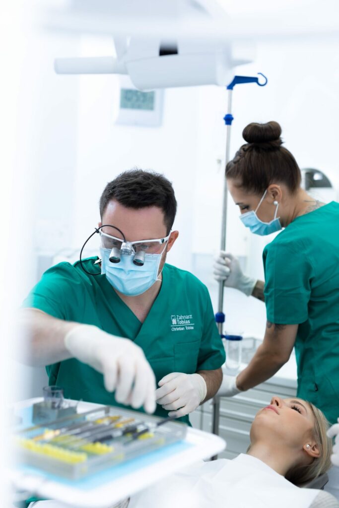 Patientin liegt auf dem Behandlungsstuhl und wartet auf die Behandlung während der Arzt nach den Behandlungsinstrumenten greift