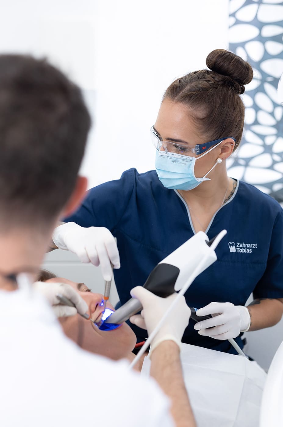 Eine Zahnmedizinsche Fachangestellte behandelt gemeinsam mit einem Zahnarzt eine Patientin