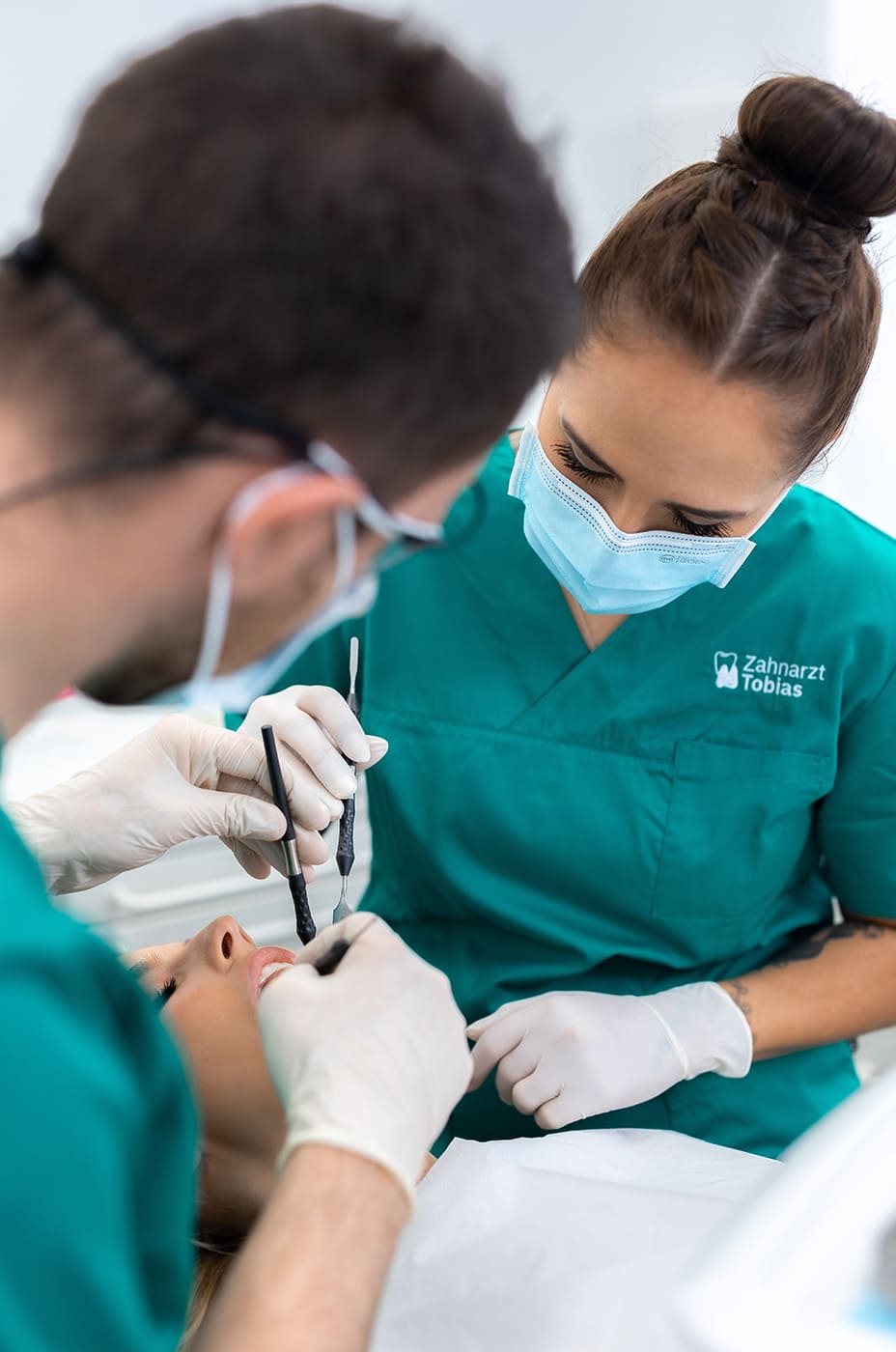 Eine Zahnmedizinsche Fachangestellte behandelt gemeinsam mit einem Zahnarzt eine Patientin